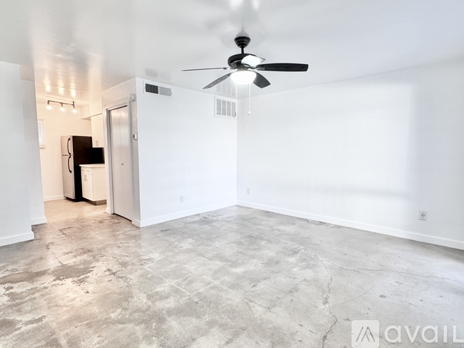 A spacious room with a ceiling fan and a door leading to another room.