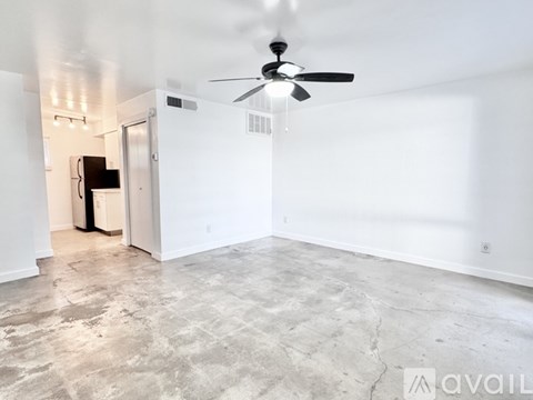 A spacious room with a ceiling fan and a door leading to another room.