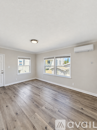 A room with wooden flooring and a window overlooking a patio.