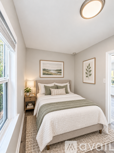 A bedroom with a bed, nightstand, and framed pictures on the wall.