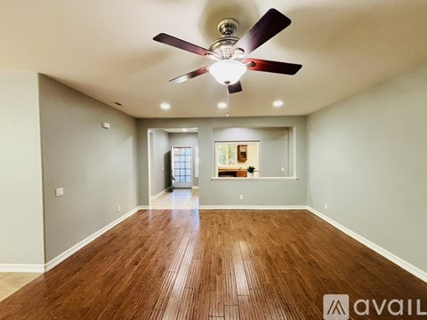 A room with a ceiling fan and wooden flooring.