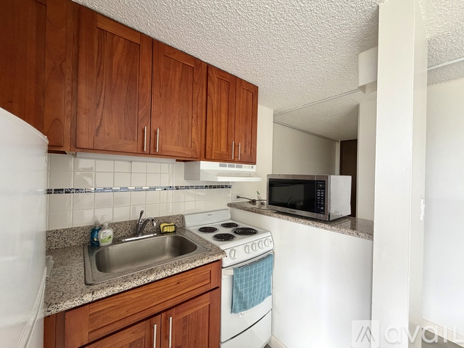 A kitchen with brown cabinets and a white stove top oven.