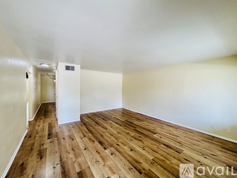 A room with wooden flooring and white walls is available for rent.