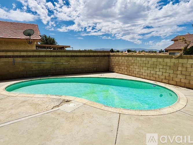 A pool with a wall around it and a house in the background.