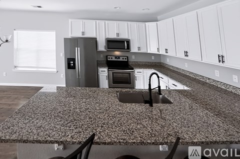 A kitchen with a granite countertop and white cabinets.