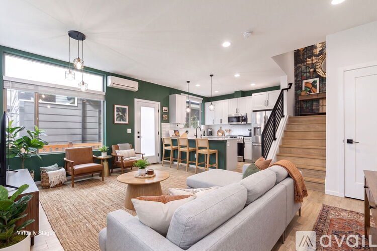 A living room with a grey couch and a staircase.