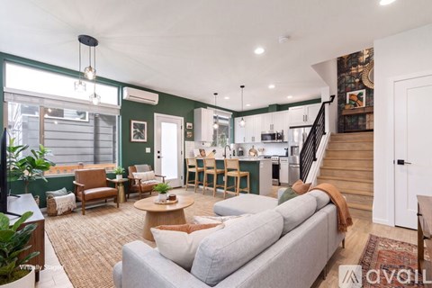 A living room with a grey couch and a staircase.