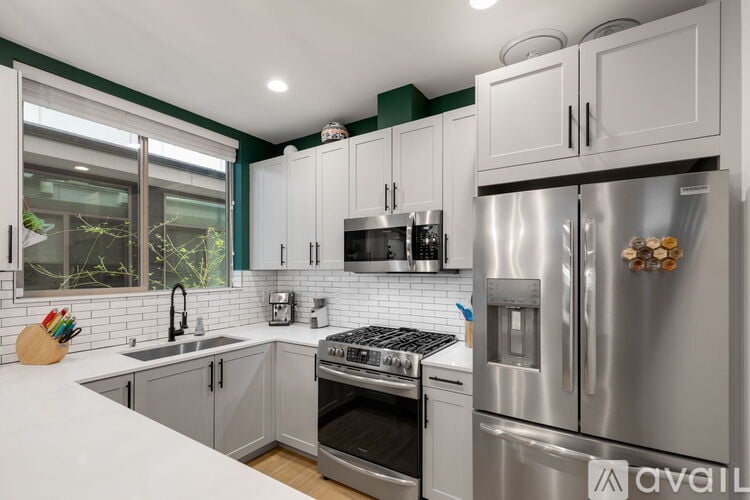 A kitchen with a stainless steel refrigerator and white countertops.