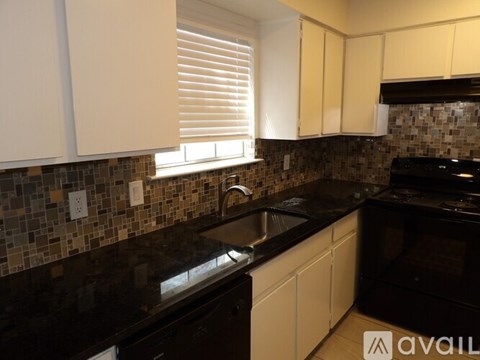 A kitchen with black granite countertops and white cabinets.