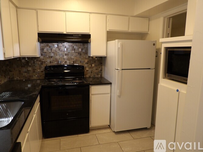A kitchen with black appliances and white cabinets.