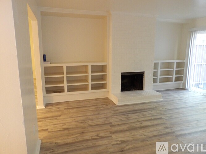 A living room with a fireplace and built-in shelves.