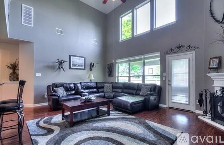 A living room with a black leather couch and a wooden coffee table.