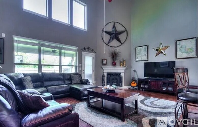 A living room with a leather couch, a coffee table, and a television.
