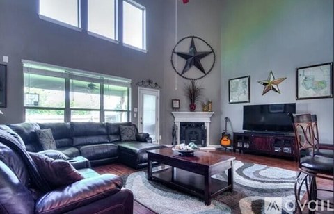 A living room with a leather couch, a coffee table, and a television.