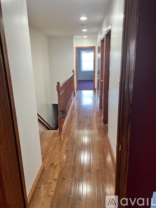 A hallway with wooden floors and white walls.
