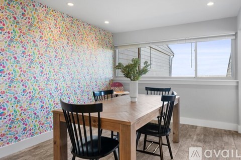 A dining room with a table and chairs and a wallpapered wall.