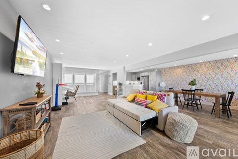 A modern living room with a large sofa, a television, and a dining area with chairs and a table.