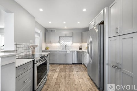 A modern kitchen with stainless steel appliances and wooden flooring.