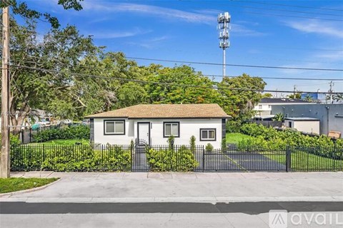 A small house with a black fence is for sale.