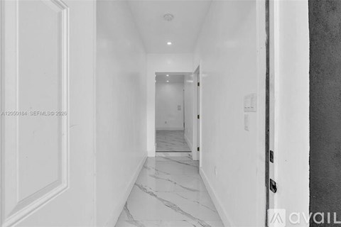 A long white hallway with marble flooring and white walls.