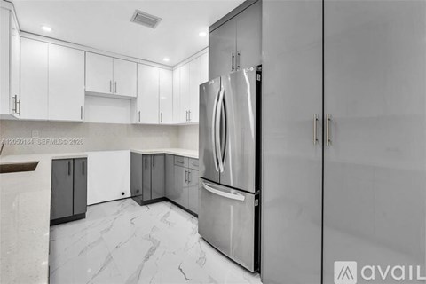 A modern kitchen with a stainless steel refrigerator and white cabinets.