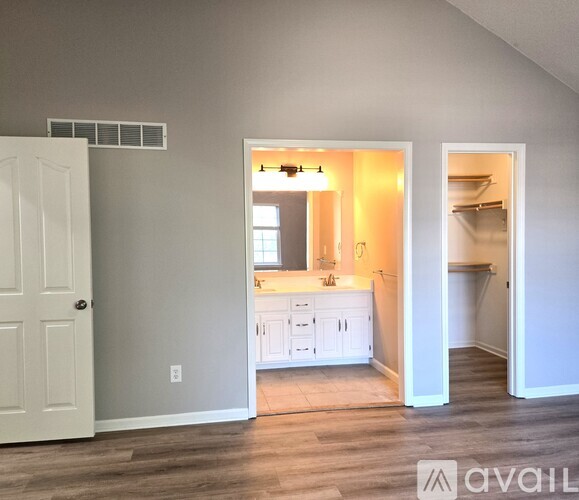A kitchen with white cabinets and a wooden floor is visible through an open door.