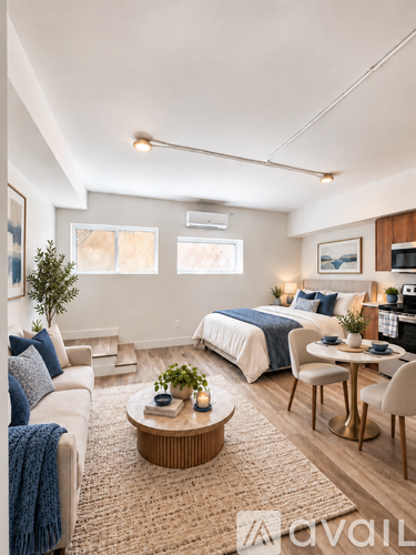 A well-lit bedroom with a bed, a couch, a table, and a plant.