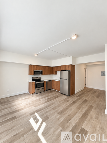 A kitchen area with wooden floors and a refrigerator.