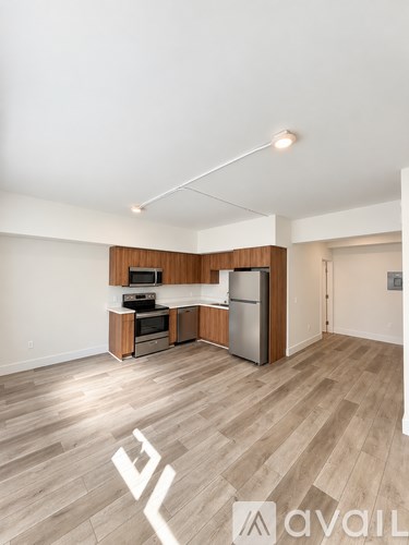 A kitchen area with wooden floors and a refrigerator.