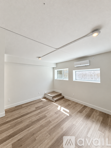 A room with wooden flooring and a window showing a view of trees.