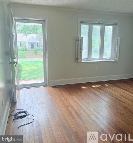 A room with a wooden floor and a window with blinds.
