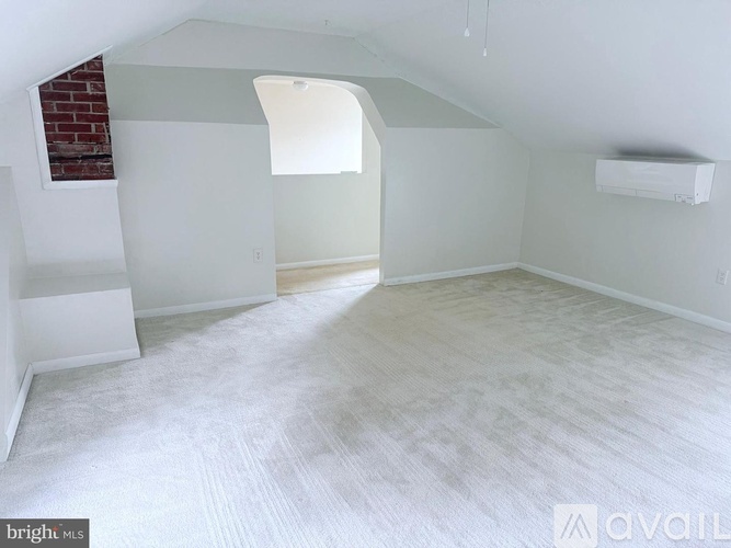 A spacious room with a brick wall and a window.