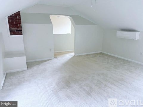 A spacious room with a brick wall and a window.