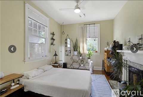 A bedroom with a bed, a desk, and a fireplace.