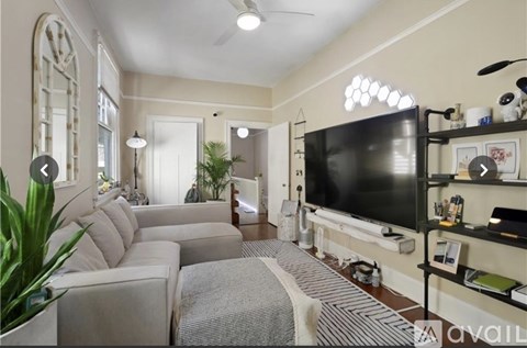 A living room with a large couch and a television on the wall.