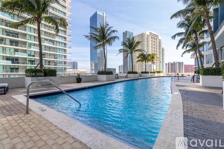 A pool surrounded by palm trees and buildings.