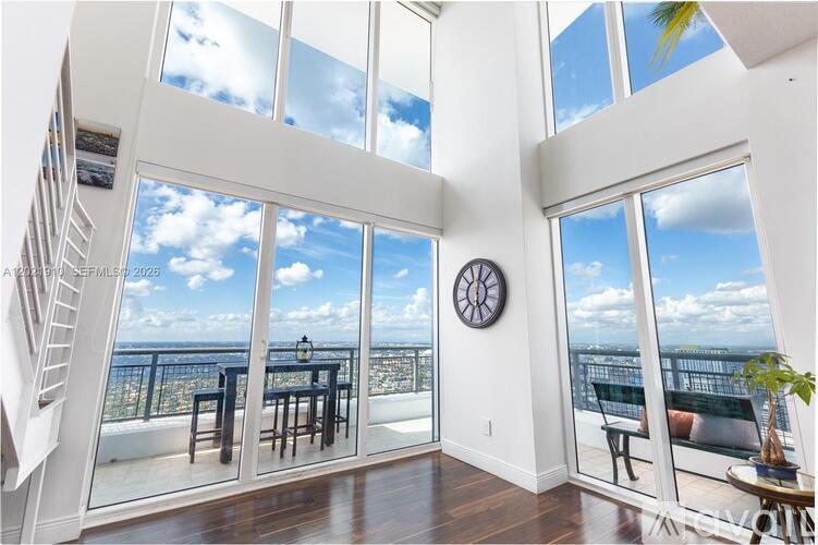 A sunny day at the beach is visible from the large windows of this spacious room.