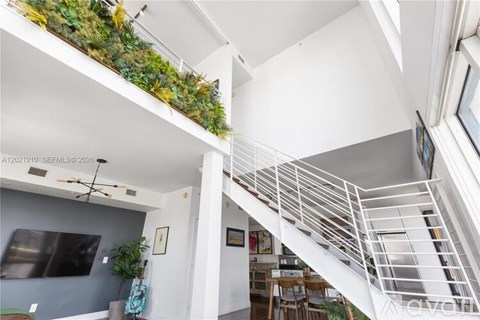 A living room with a couch and a green plant on the wall.