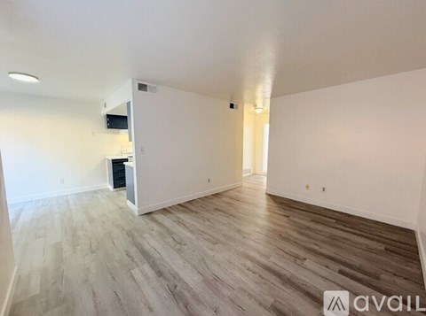 A spacious room with wooden flooring and white walls.