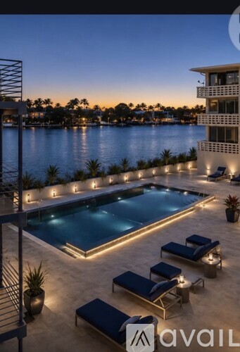 A pool with loungers and a building in the background at dusk.