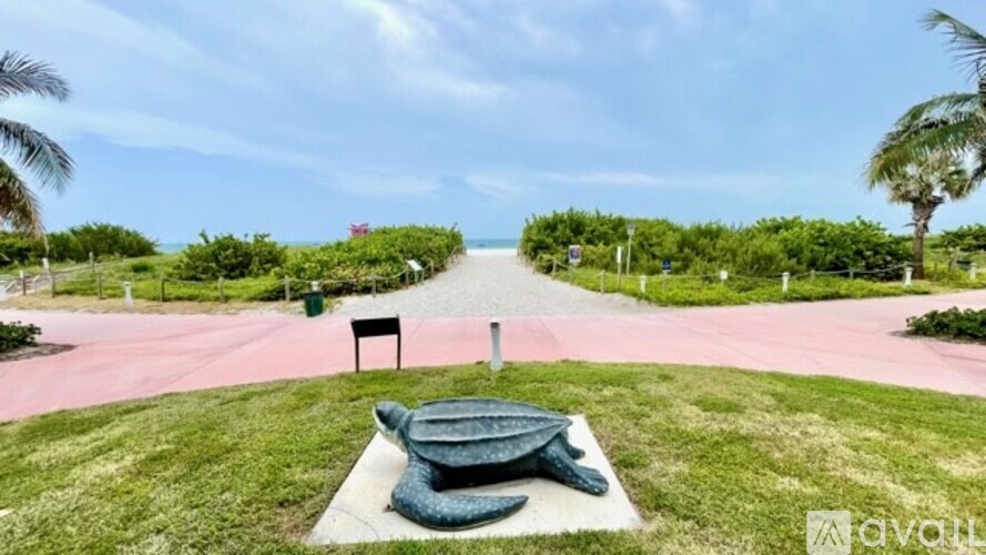 A turtle statue is sitting on a concrete slab in the middle of a grassy area.