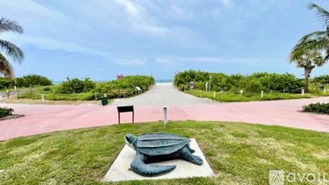 A turtle statue is sitting on a concrete slab in the middle of a grassy area.