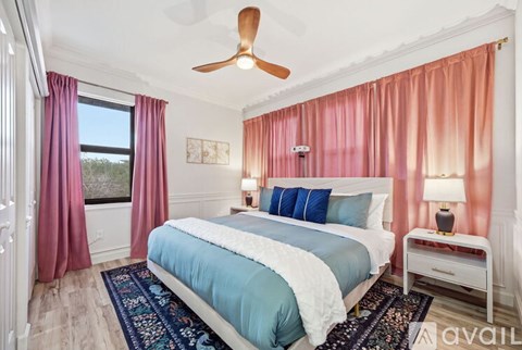 A bedroom with a large bed and a ceiling fan.