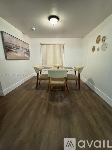 A room with a wooden floor and a dining table with chairs.