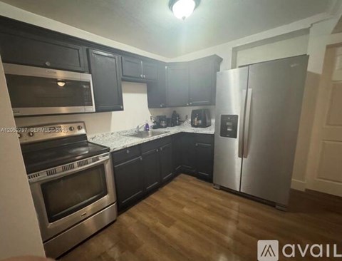 A kitchen with black cabinets and stainless steel appliances.