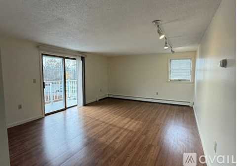 A room with wooden floors and a window with blinds.