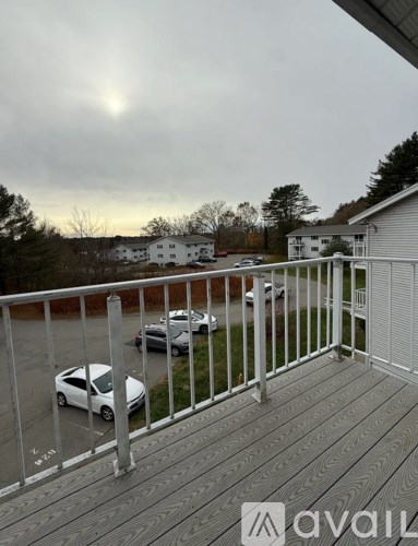 A balcony with a railing and a car parked in the driveway.