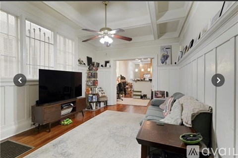 A living room with a television and a rug.