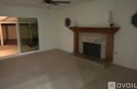 A living room with a fireplace and a fan on the ceiling.