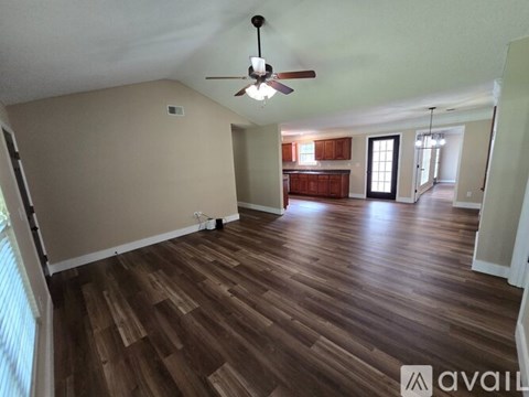 A spacious room with wooden flooring and a ceiling fan.